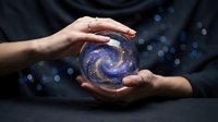 Hands protecting glowing spiral galaxy in cosmic sphere against dark background with bokeh lights for mystical energy and universe concepts.