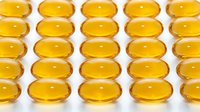 Golden yellow omega-3 fish oil capsules arranged in neat rows on white background. Supplement and wellness concept for health, nutrition, and dietary supplement marketing.