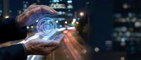 Businessman hands protecting glowing digital shield icon with cybersecurity concept against blurred city lights background for data protection solutions.