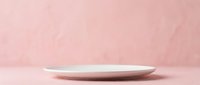 Empty white plate on soft pink textured background, suitable for food styling, product mockups, and culinary design projects.