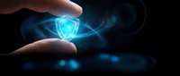 Hand holding glowing blue shield symbol with light rays representing cybersecurity protection and digital safety in dark environment.