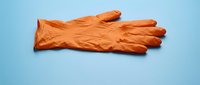 Pair of orange latex gloves isolated on blue background, ready for design use in healthcare, cleaning, and safety applications.
