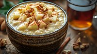 Creamy rice pudding topped with diced pineapple and crushed pecans in rustic ceramic bowl, served with honey and cinnamon on wooden table, comfort food styling.