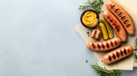 Grilled sausages with mustard sauce, pickled cucumber and fresh rosemary on light background with copy space. Food photography for menu design.