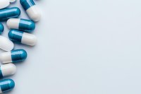 Blue and white medical capsules arranged on light blue background with copy space, creating minimalist pharmaceutical composition for healthcare concepts.