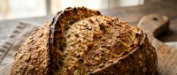 Whole coconut with textured brown husk on wooden surface, suitable for food, culinary, and tropical ingredient stock photography.