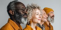 Diverse group of senior adults with gray hair wearing mustard yellow clothing against light background, showcasing aging with confidence and style.