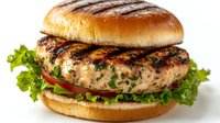 Grilled chicken sandwich with fresh lettuce, tomato and herbs on golden brioche bun against white background, close up view of juicy meat patty.