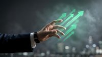 Businessman hand reaching for glowing green upward arrows representing growth, success, and financial progress in corporate environment.