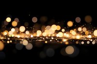 Magical golden bokeh lights scattered on dark background with glowing particles and sparkles creating dreamy atmospheric effect.