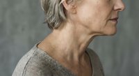 Mature Caucasian woman in profile showing natural aging process with gray hair and wrinkles for skincare and wellness concepts.