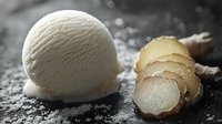 Fresh ginger root sliced next to scoop of vanilla ice cream on dark textured surface with scattered powdered sugar creating contrast and culinary composition.