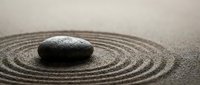 Zen garden with black stone on raked sand circles creating peaceful meditation space for mindfulness and relaxation practices.