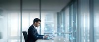 Professional businessman working on laptop in modern glass office with city view, corporate executive at desk analyzing data and digital technology interface.