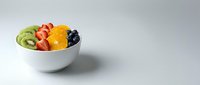 Fresh sliced kiwi, strawberry, orange and blueberry arranged in white bowl on neutral background for healthy eating and nutrition content.