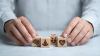 Hands protecting wooden blocks with health and wellness icons including brain, meditation, leaf and heart symbols for healthcare concept.
