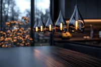 Modern glass pendant lights with warm glowing candles create cozy atmosphere in dark interior against window with autumn trees outside.