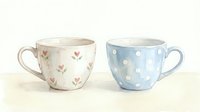 Two ceramic teacups with floral and polka dot patterns, isolated on white background, ready for product design, home decor, tableware, and kitchenware projects.