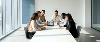 Diverse business team collaborating in modern conference room with natural lighting and contemporary office design for corporate meetings.