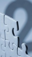 Close-up macro shot of metallic silver jigsaw puzzle pieces connecting together with shallow depth of field and soft blue background for business concepts.