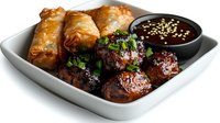 Asian appetizer platter with glazed meatballs, spring rolls and dark dipping sauce garnished with sesame seeds and fresh herbs served on white plate.