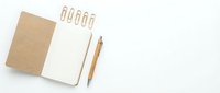 Open kraft notebook with blank page, wooden pen, and gold paper clips on white background, flat lay for business or study.