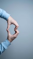 Two hands reaching toward each other in blue sleeves against gray background symbolizing connection, teamwork, partnership and human interaction.