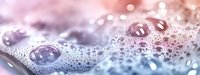 Water droplets on surface with soft pink and purple bokeh lights creating dreamy atmospheric background for spa wellness and relaxation concepts.