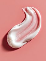 Swirled white cream texture with sparkles on coral pink background, cosmetic skincare product smear showing smooth luxurious consistency for beauty advertising.