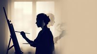 Silhouette of a female artist painting on canvas with easel, backlit by bright window light creating artistic shadow effect.