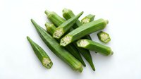 Fresh green okra pods with sliced pieces showing seeds, isolated on white background for healthy cooking and vegetable design projects.