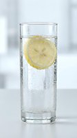 Glass of sparkling water with fresh lemon slice and ice bubbles, refreshing beverage for hydration, wellness, and summer drink concepts.