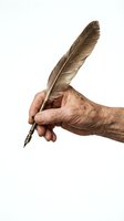 Elderly hand holding vintage feather quill pen on white background, isolated for writing and calligraphy design projects.