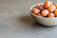 Fresh ripe apricots in modern ceramic bowl on gray marble surface with copy space, natural light food photography for healthy eating concept.