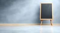 Empty black chalkboard on wooden easel against gray wall with copy space, minimalist education background for presentation mockup or classroom design.