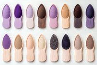 Makeup sponges in various shapes and colors arranged in neat rows on white background. Professional beauty blenders for foundation and cosmetic application.