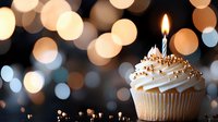 Vanilla cupcake with lit blue candle against blurred golden bokeh lights background, decorated with sprinkles and whipped cream frosting for celebration moments.
