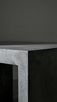 Minimalist concrete table corner detail with raw industrial texture against neutral gray background for modern interior design projects.