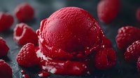 Fresh raspberry sorbet scoop on dark background surrounded by whole ripe berries, with melting texture and vibrant red color creating appetizing dessert composition.