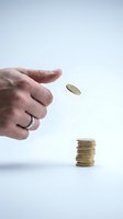 Hand tossing gold coin above stack of coins on white background, symbolizing investment, savings, financial growth, and money management for business concepts.