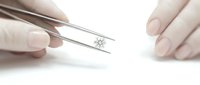 Jeweler holding a sparkling round brilliant diamond with tweezers, close-up view for luxury jewelry, gemology, and retail concepts.