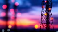 Silhouette of telecommunications tower against dramatic sunset sky with pink and purple hues, defocused bokeh lights creating atmospheric communication concept.