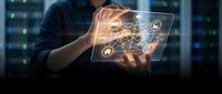 Young male professional holding transparent digital tablet displaying glowing network connections and technology icons, representing data management, cloud computing, and digital transformation in modern business environment.
