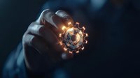 Glowing mechanical gear held between fingers against dark background, illuminated with warm light creating mysterious technological atmosphere.