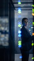 Professional businesswoman standing by office window at night with colorful city lights bokeh background for corporate and leadership concepts.