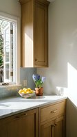 Modern kitchen corner with natural wood cabinets, marble countertop, and spring hyacinth flowers creating warm homey atmosphere for interior design.