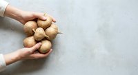 Hands holding fresh potatoes on light background, suitable for organic food, agriculture, and cooking content.