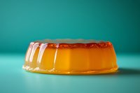 Orange jelly dessert on turquoise background with soft shadows and reflections, showing translucent texture and wobbling surface of caramel pudding.