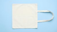Blank cream cotton tote bag with handles isolated on light blue background, ready for custom design, branding, printing, or merchandise mockup projects.