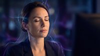 Young woman with dark hair and fair complexion wearing business attire in futuristic neon-lit environment with digital effects and bokeh lighting.